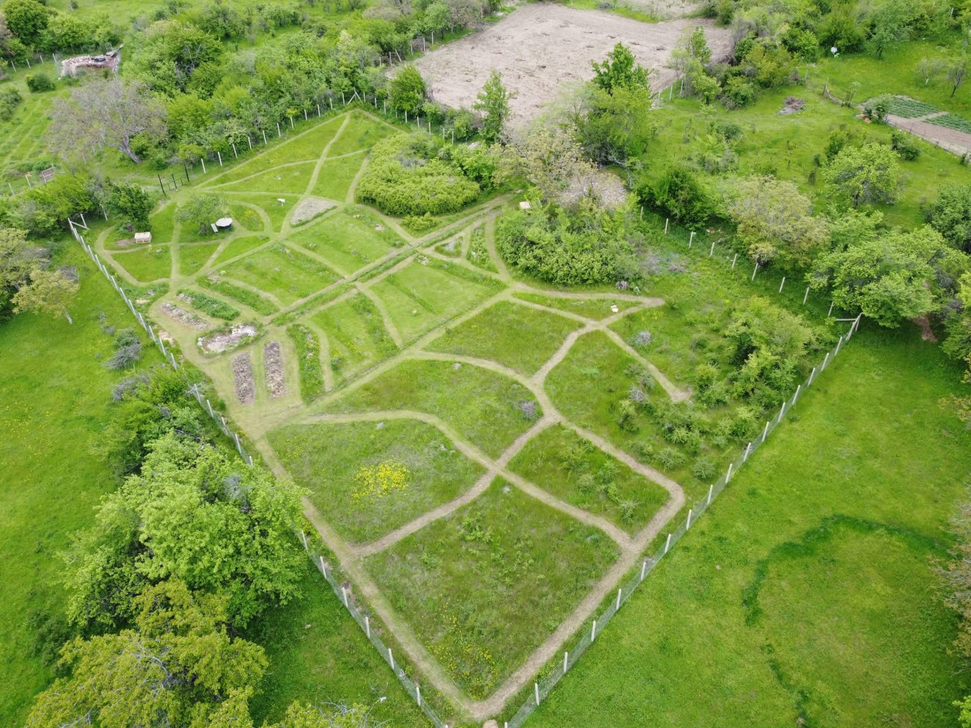 Zračni pogled na permakulturni sadovnjak s potmi in zasajenimi površinami